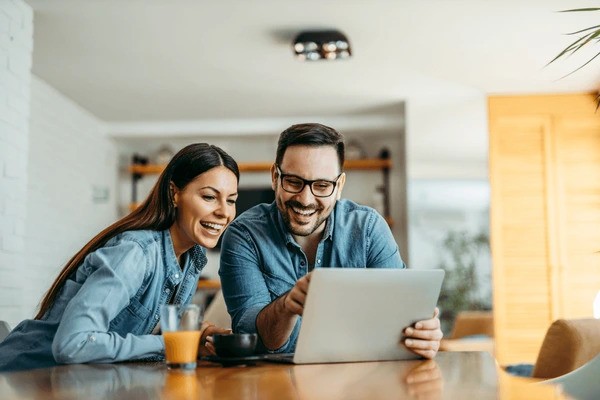 two people on a laptop smiling