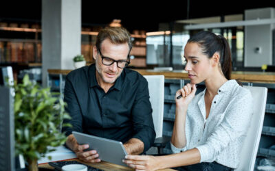 Male and female colleagues looking at tablet PC. Business people are working at desk.