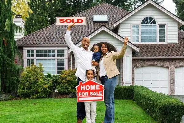 family in front yard of new home holding a sold sign