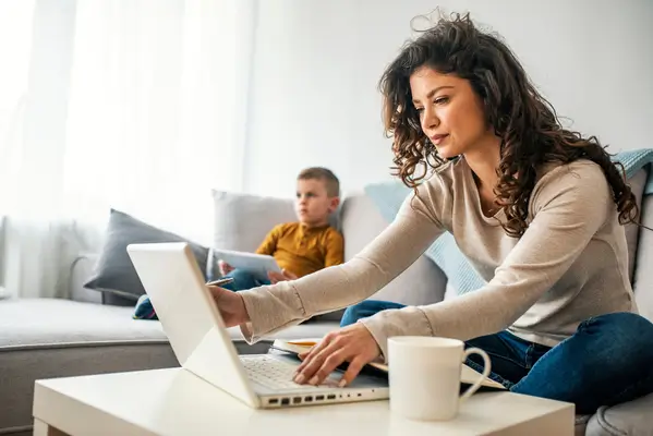 woman on laptop with son in background