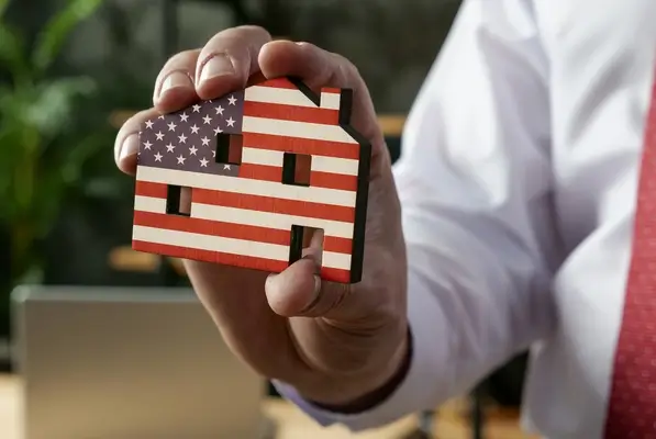 guy holding a wooden home with the american flag painted on it