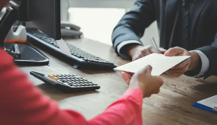 woman being handing a paper by a man at a desk