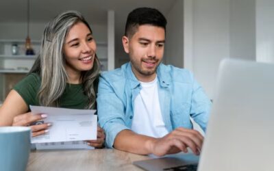 couple sitting at a desk looking at a computer.