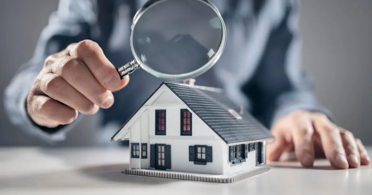 Magnifying glass over small house model during home appraisal review