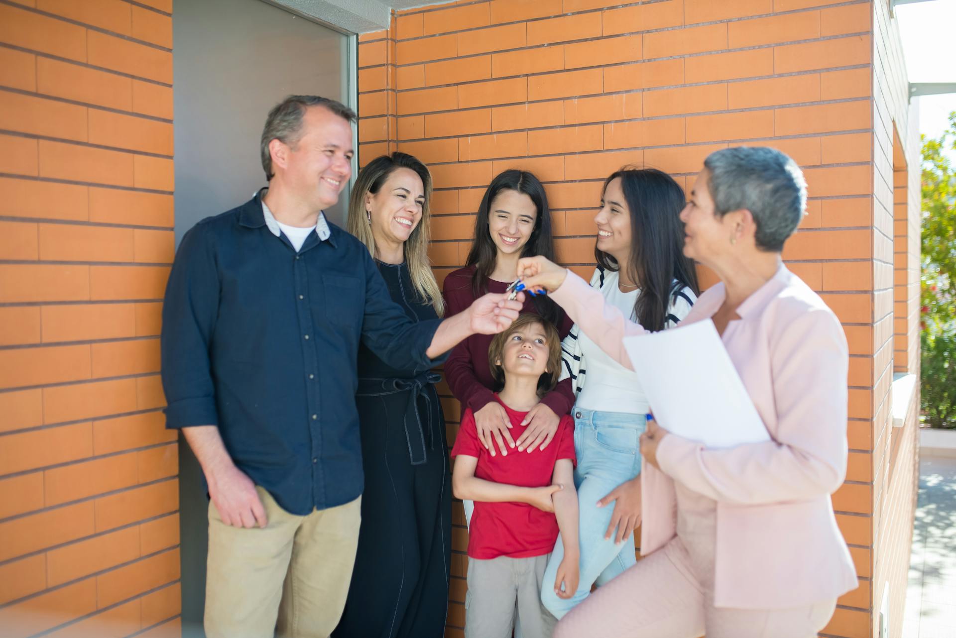 Family with children joyfully receiving keys to their new home